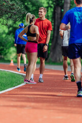 Young couple stretching before starting their morning jogging routine on a tartan track at the park.