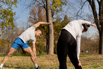 Two friends warming up and stretching together in the park