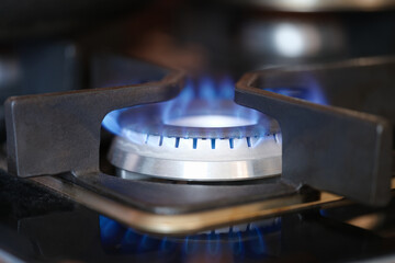 Gas burner on stove with blue fire at home closeup