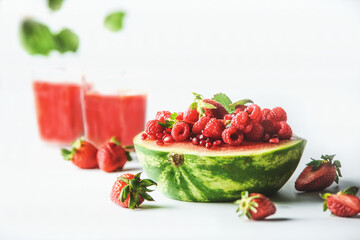 Watermelon halve served with red summer fruits, berries and red juice: strawberries and raspberries...