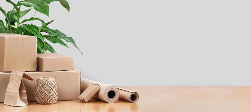 Assorted buff paper packaging carry bags and boxes on desk. Delivery service of goods and grocery, shopping courier. Environment and eco friendly packaging, plastic free small business banner