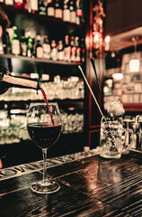 bartender pouring red wine into a glass in cafe or bar on the bar counter