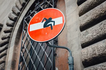 Rolgordijnen Street art road sign stop on the street of Florence - a figure of man climbs out of the sign © Denys Poliakov