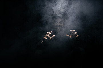 Fototapeta na wymiar smoke clouds arround man with a hat on dark background