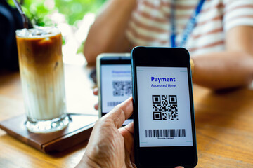 Smartphone in hand to scan QR code payment tag and blurry ice coffee with milk in restaurant to accepted generate digital pay without money. Qr code payment concept.