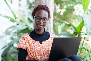 Young African student with her laptop working at home for her exam; e-learning and distance...