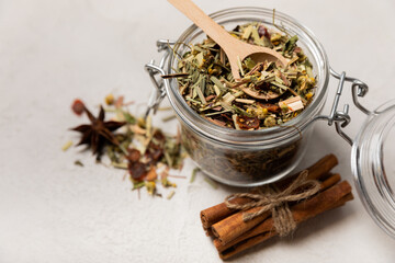 Aromatic herbal tea in a glass jar on a light gray background. Tea set with lemon, cinnamon, ginger and anise. Immune and vitamin tea. Cold drink. 