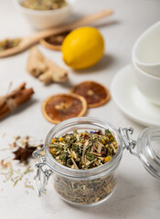 Aromatic herbal tea in a glass jar on a light gray background. Tea set with lemon, cinnamon, ginger and anise. Immune and vitamin tea. Cold drink. side view.