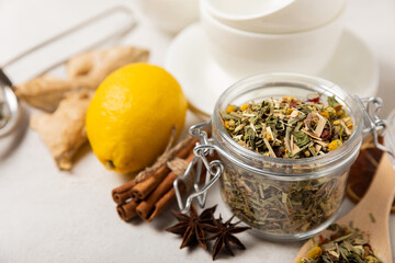 Aromatic herbal tea in a glass jar on a light gray background. Tea set with lemon, cinnamon, ginger and anise. Immune and vitamin tea. Cold drink. side view.