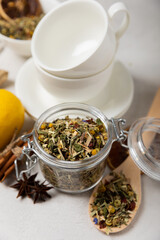 Aromatic herbal tea in a glass jar on a light gray background. Tea set with lemon, cinnamon, ginger and anise. Immune and vitamin tea. Cold drink. side view.