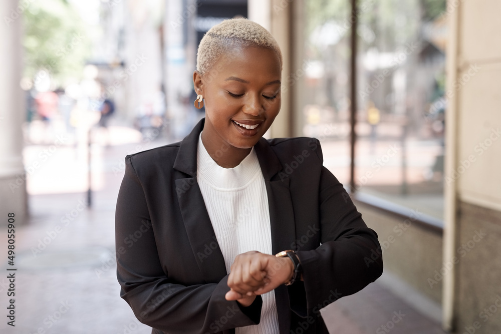 Poster staying on track and on time. shot of a young businesswoman checking the time on her wristwatch whil