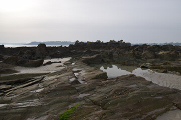Fototapeta na wymiar Rough, rocky coast of Brittany, France, with reflections in the water