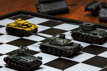Toy tanks on a chessboard. The concept of military strategy.
