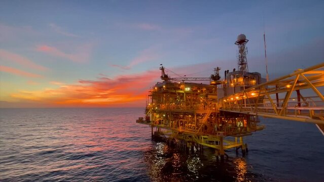 offshore oil and gas platform in sunset time the platform produced raw gases and crude oil for sent to onshore refinery, petrochemical plant and tanker for export for industry concept.