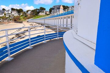 Obraz premium Bright blue beach huts on sandy beach with town in the background