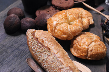 Croissant, bread and cookies on dark gray wooden floor