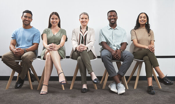 Confident and keen to prove their talent. Portrait of a group of businesspeople sitting together in a line against a white wall.