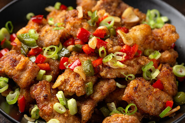 Stir fry salt and pepper pork loin with herbs in black bowl. Asian food