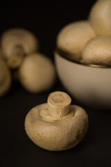 Champignon mushrooms in a plate on a dark background, ready for cooking.