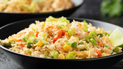 Prawn fried rice with eggs and vegetables in black bowl. Healthy asian food.