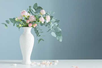 bouquet of pink roses in ceramic white vase  on blue background