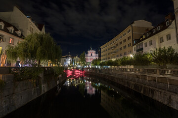 Fototapeta na wymiar Panorama of Ljubljanica river with Tromostovje (triple most) bridge in Ljubljana, capital city of Slovenia, taken during a summer night. this bridge is considered to be one of main symbols of the city