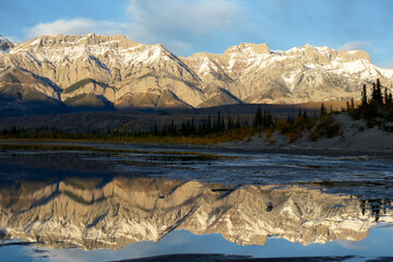  Snow-white Rocky Mountains are reflected in the blue lake in the morning light as in a mirror.