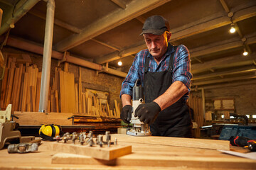 Senior Professional carpenter in uniform working of manual milling machine in the carpentry workshop