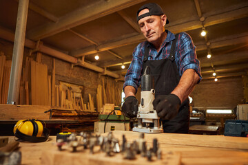 Senior Professional carpenter in uniform working of manual milling machine in the carpentry workshop