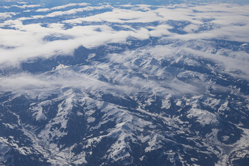 Visão área de montanhas com nuvens e neve.
