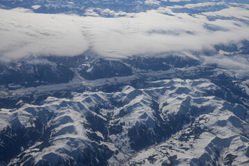 Visão área de montanhas com nuvens e neve.