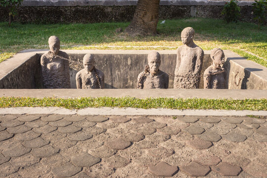 02/18/2022 - Stone Town, Zanzibar: Memorial of african slave market. Sculptures of slaves in chain in hole. Humanity concept. Abolition movement. Cruelty concept. Freedom concept. Slavery history.