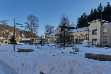 Fototapeta na wymiar Janske Lazne, Czech Republic - February 13, 2022 - The park in front of the colonnade on a sunny winter day 