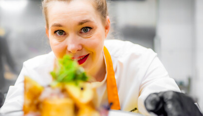 Portrait of woman chef with plate of food on kitchen