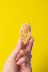 Holding a fried snack chicken nuggets on an yellow background in your hand