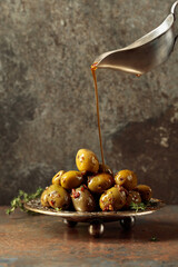 Spicy green olives are poured with olive oil with spices.