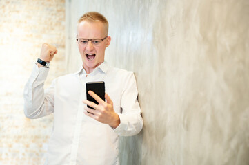 Young businessman handsome feeling excited and surprise with mobile smartphone