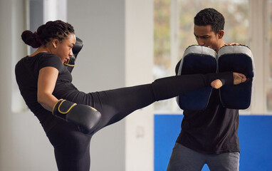 Kickboxing is the best form of dynamic exercise. Shot of a young woman practicing kickboxing with...