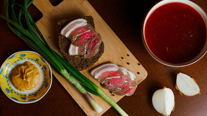 Delicious tender bacon with onions and bread on a wooden board in the house