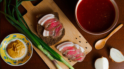 Delicious tender bacon with onions and bread on a wooden board in the house