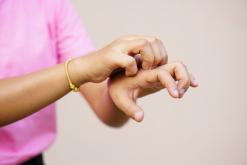 Woman scratching arm from itching on light gray background. Cause of itchy skin include insect...