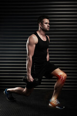 Obraz premium Lunges can put strain on your knees. Full length shot of an athletic young man working out with dumbbells in the studio.