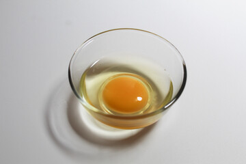 Raw egg in a glass bowl. Isolated on white background.