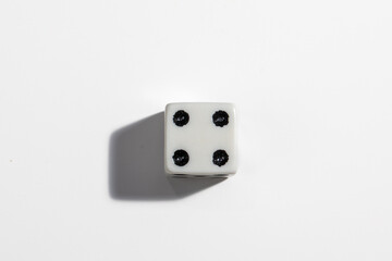 Single white dice with a four on a white background. Win or lose. Catch your luck. Gambling equipment.