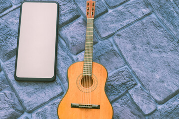 Phone with space for text, acoustic guitar on a cobbled grey blue background