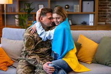Beautiful delighted woman hugging her soldier husband. Flag of Ukraine.