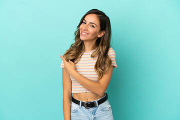 Young woman over isolated blue background pointing to the side to present a product