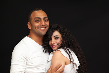 Portrait of a young couple in white t-shirts on a black background. High quality photo