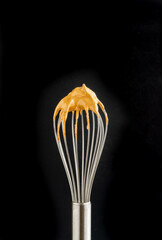 whisk with dalgona foam, preparation of whipped instant coffee cream, black background