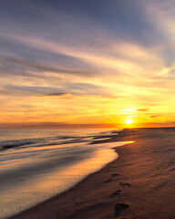 Fototapeta na wymiar Footprints leading off into the sunset along a beautiful beach. Long Island New York
